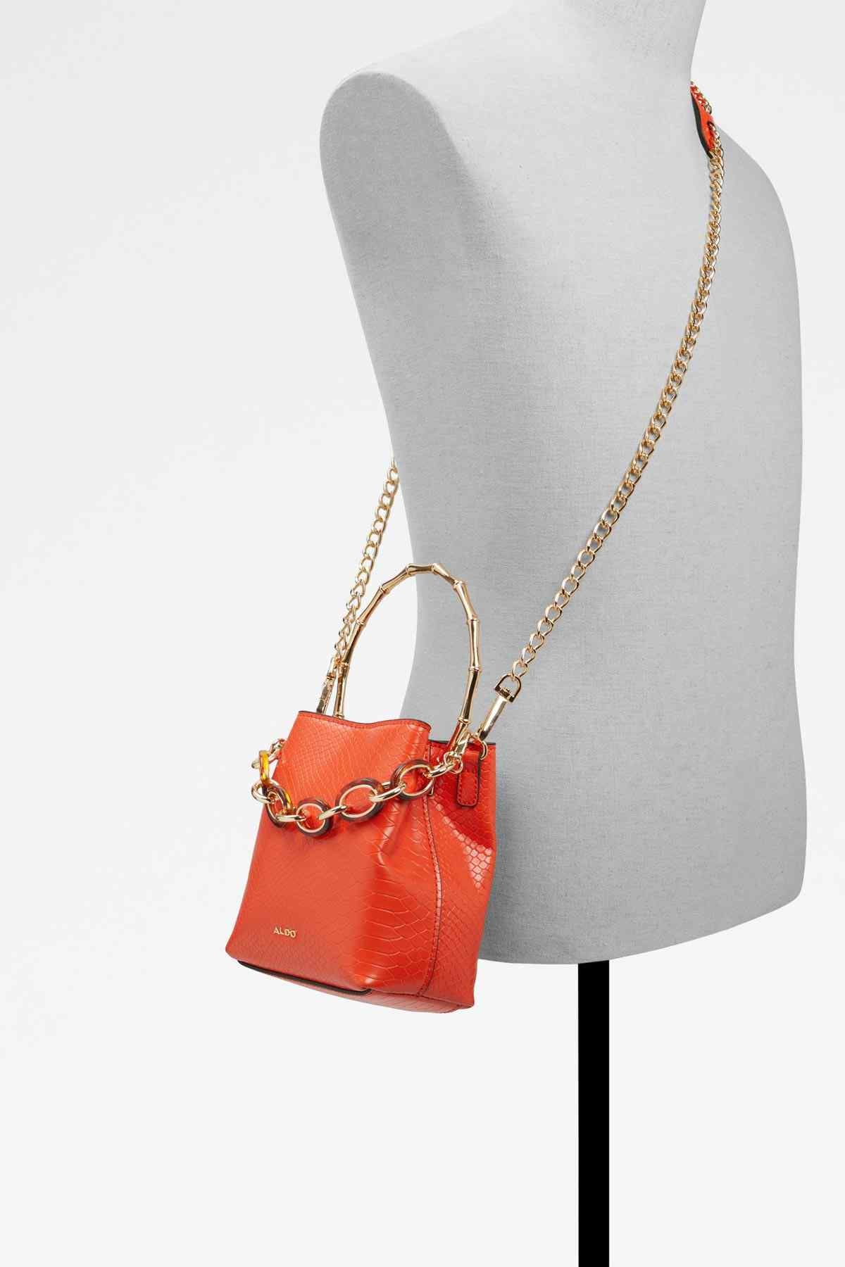 Bright orange textured leather mini handbag with gold chain shoulder strap on mannequin