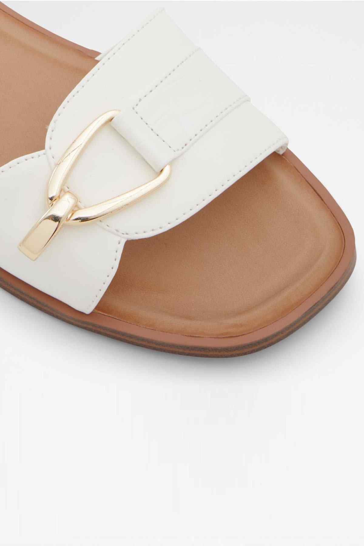 White leather slide sandal close-up: wide strap and gold-tone buckle