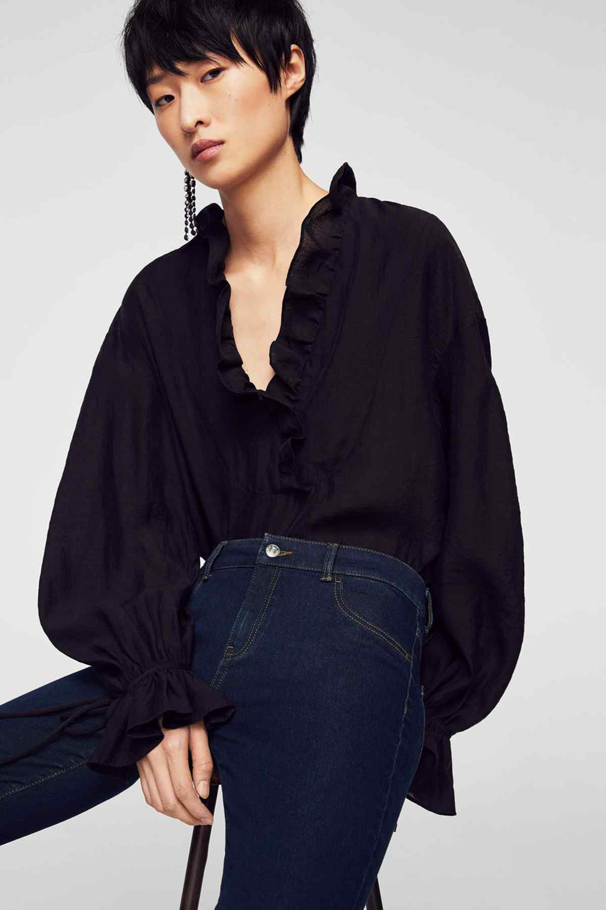Dark blue slim-fit jeans with front pockets and belt loops, with dark blouse