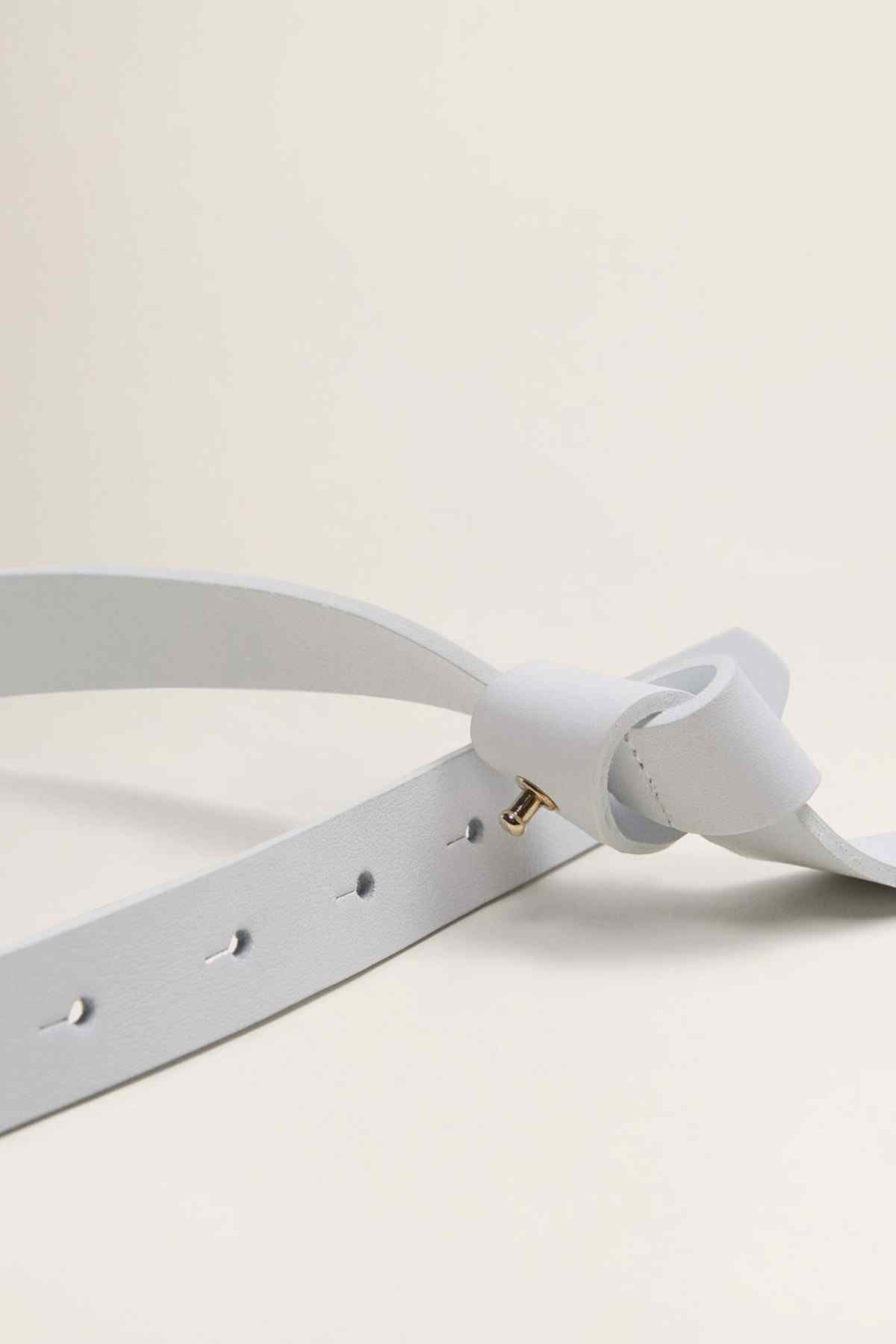 White belt detail with T buckle, gold pin, and adjustable holes