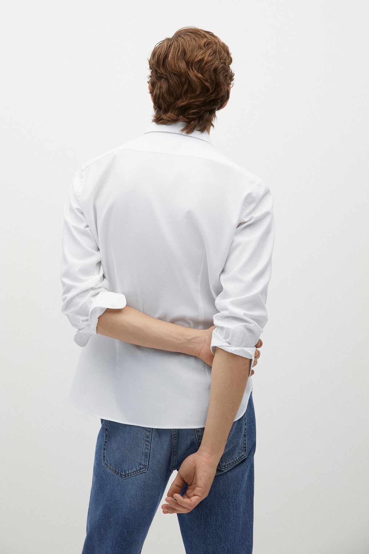 Back view of off-white button-up shirt with long sleeves and curved hem