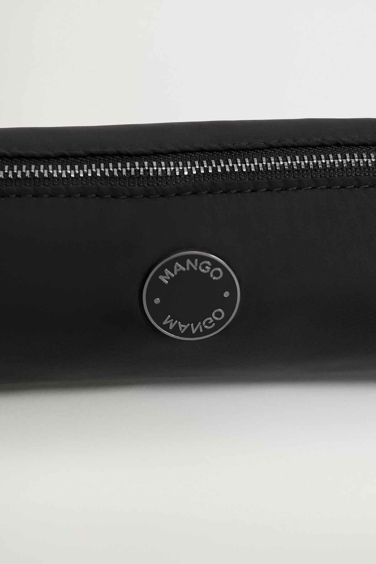 Black zip pouch close-up of round logo patch and metal zipper teeth