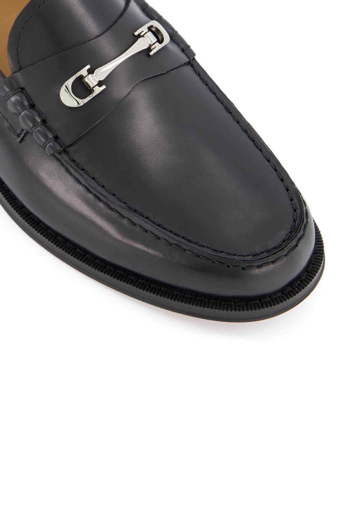 Black leather loafer close-up with metal horse-bit hardware and stitched edge details