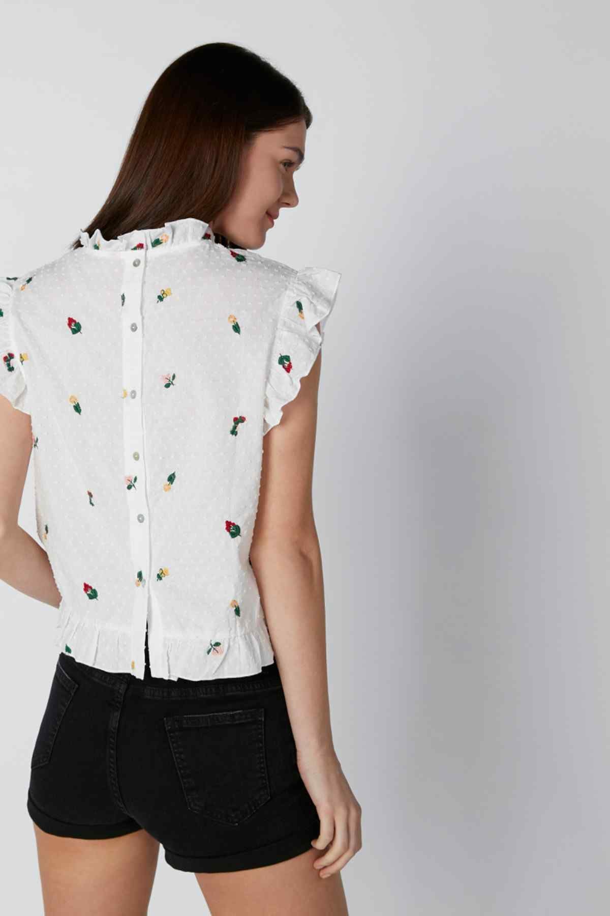 White button-up blouse with ruffled sleeves and colorful small print, side view