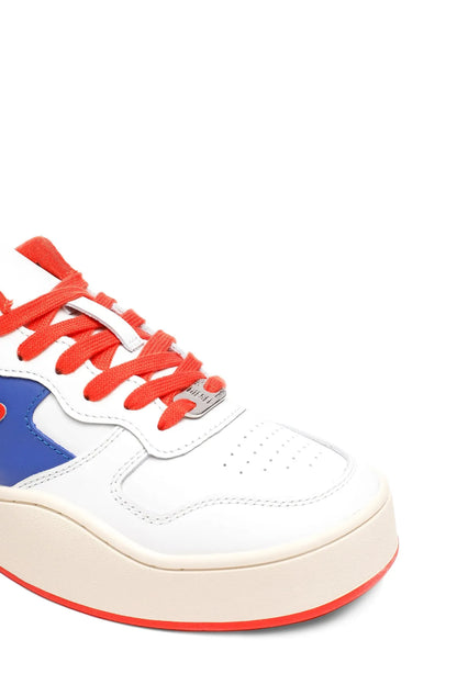White low-top sneaker close-up: blue side panel and orange lace-up