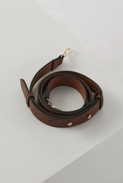 Brown leather crossbody strap with gold-tone buckle and end hardware