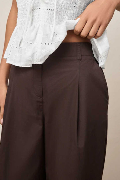 Chocolate brown trousers close-up: pleated waistband and front pockets