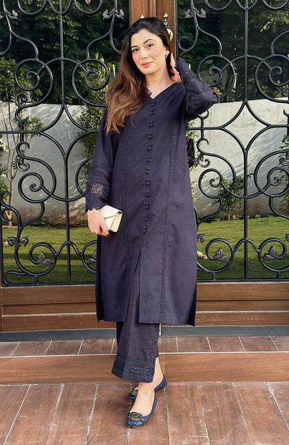Black long button-front tunic with lace cuffs and matching pants, raised-hand standing pose