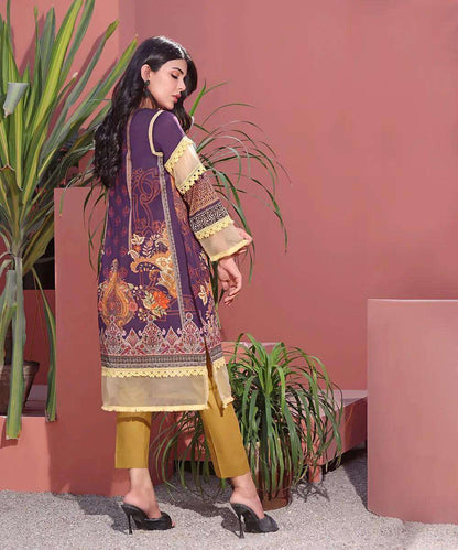 Women’s long tunic dress with patterned border and gold-trim sleeves, side view