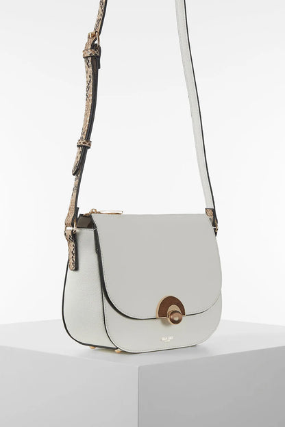 White crossbody bag with flap closure and patterned strap, angled side view