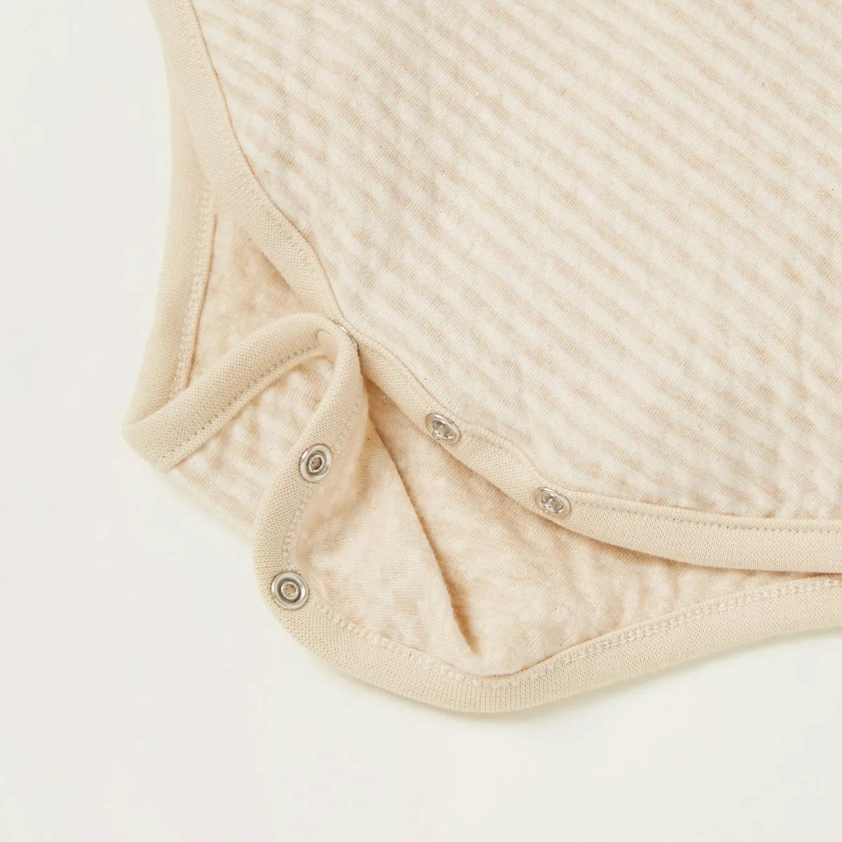 Beige striped bodysuit close-up: buttoned leg openings with snap crotch