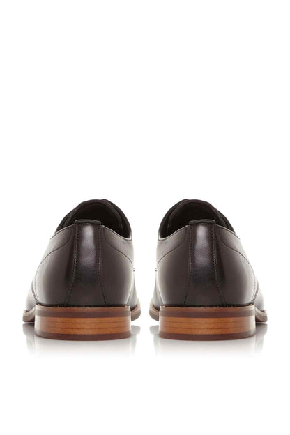 Black leather lace-up oxford shoes with heel seams and tan-trimmed soles