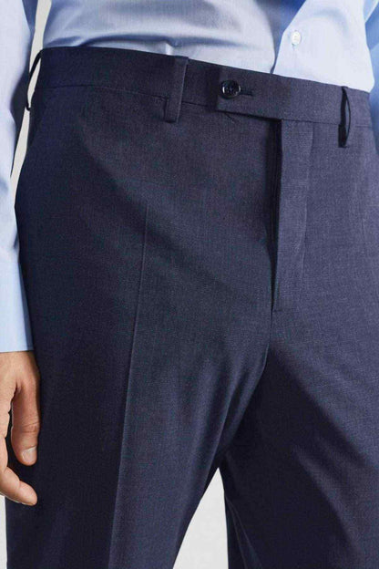 Indigo blue trousers close-up: waistband, belt loops, and front button closure