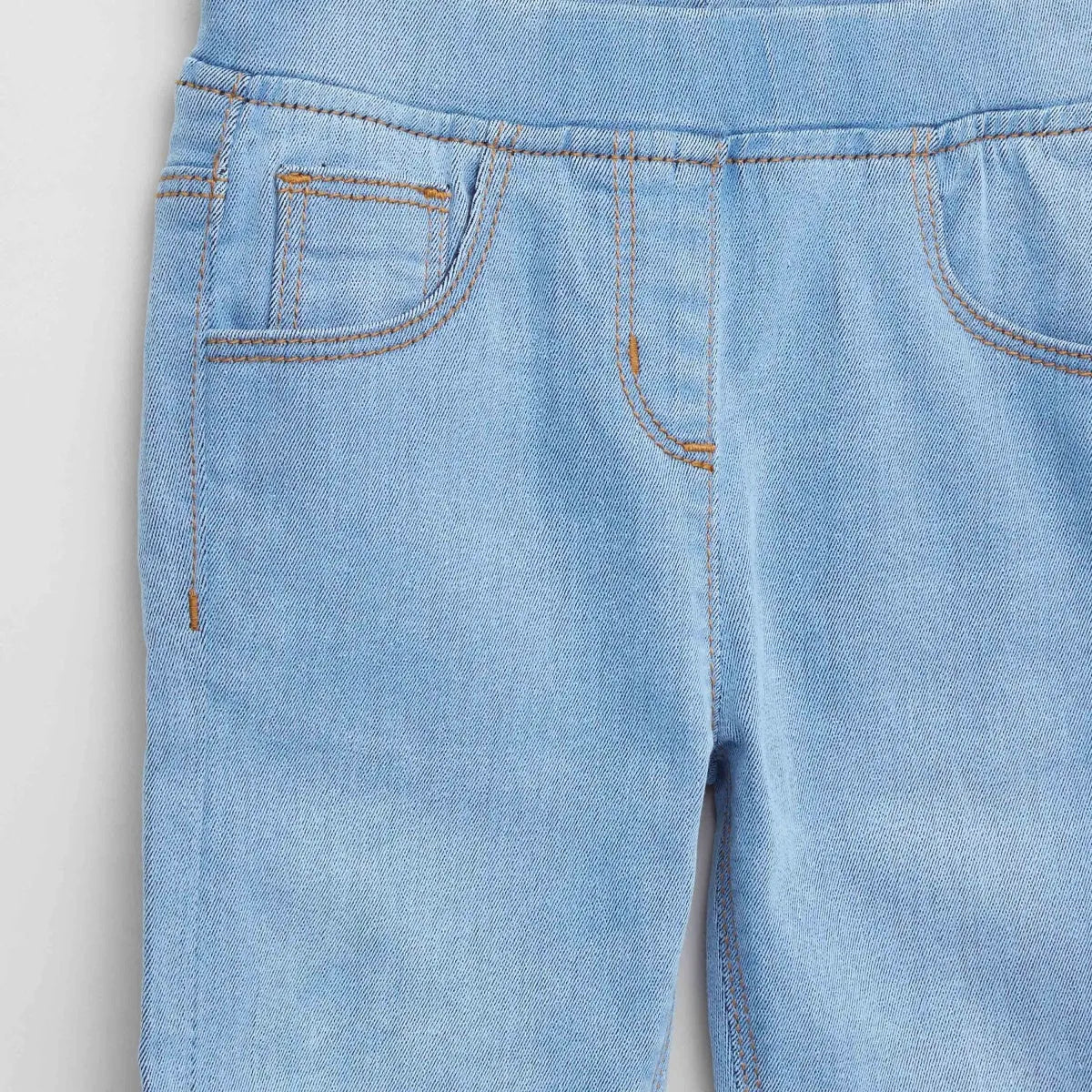 Light blue denim baby pants close-up of side seam and curved front pocket