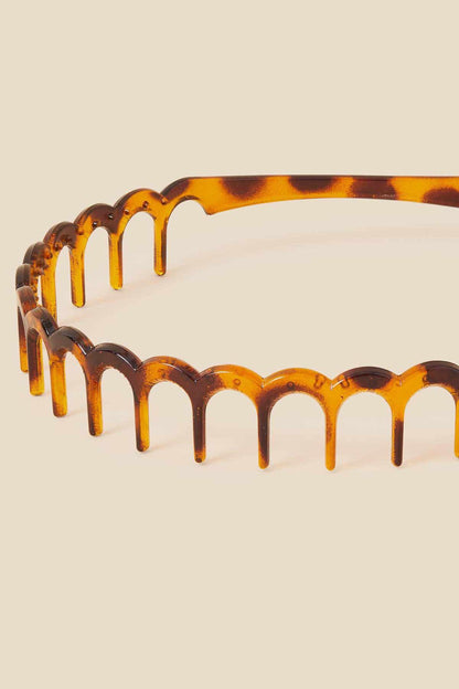 Tortoiseshell-effect hair headband close-up of side prongs, amber-brown.