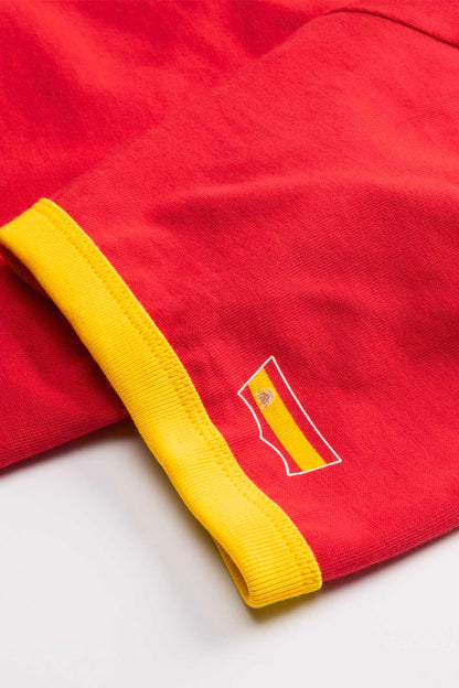 Red T-shirt with yellow ribbed trim and small flag patch