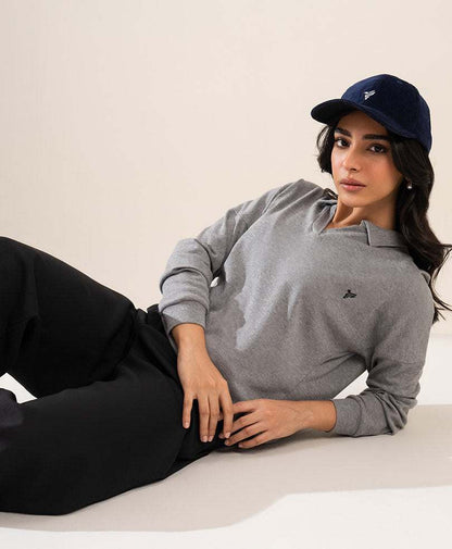 Navy fitted baseball cap with small logo, worn with grey hoodie.