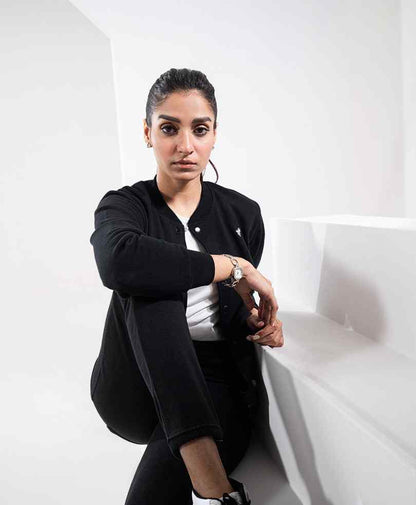 Black fitted button-front jacket with long sleeves, chest logo, and patch pockets