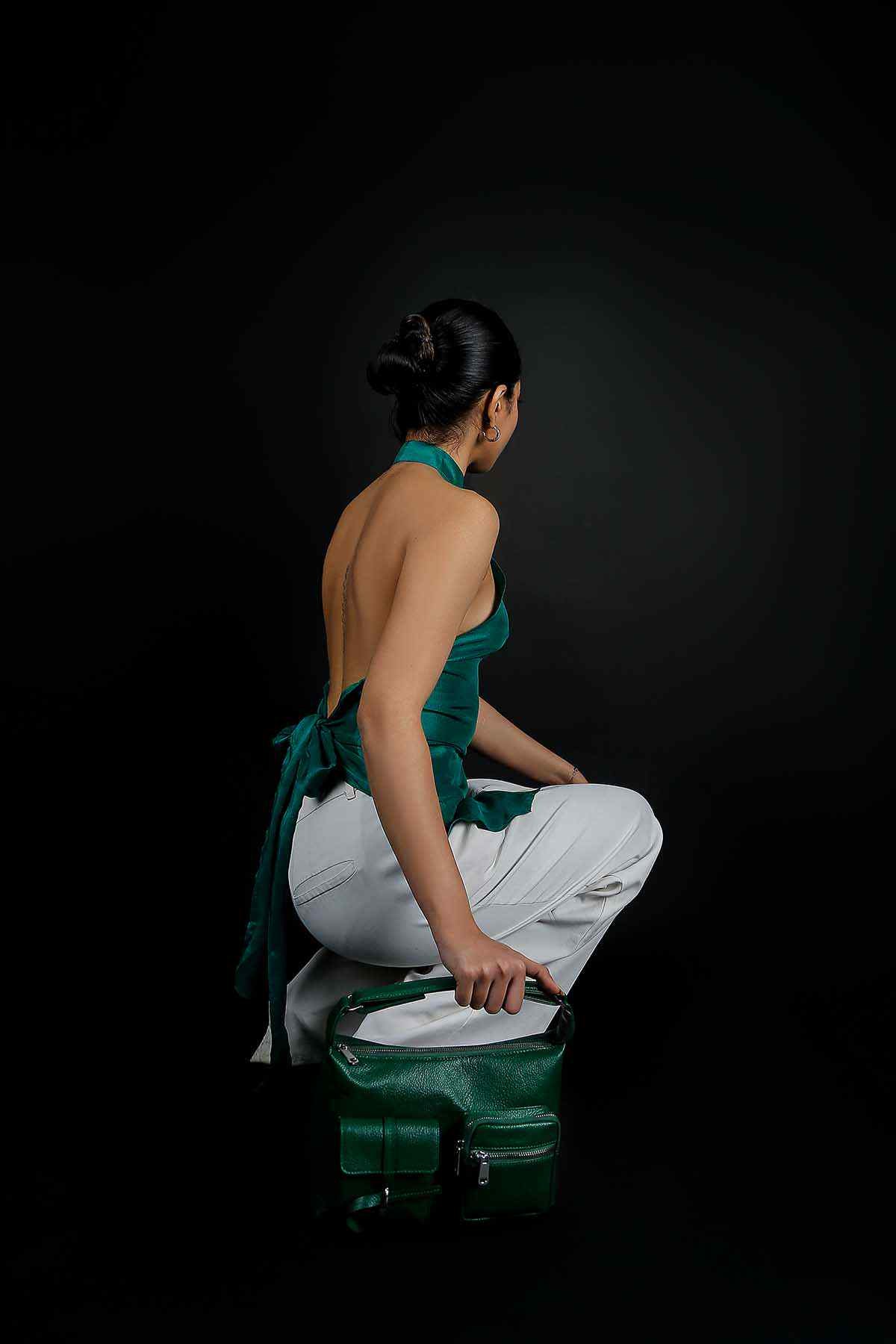 Emerald green handbag with top handle and front flap, side view