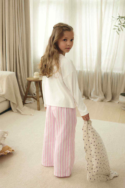 Girls' white top with pink bow and pink striped pants, side view