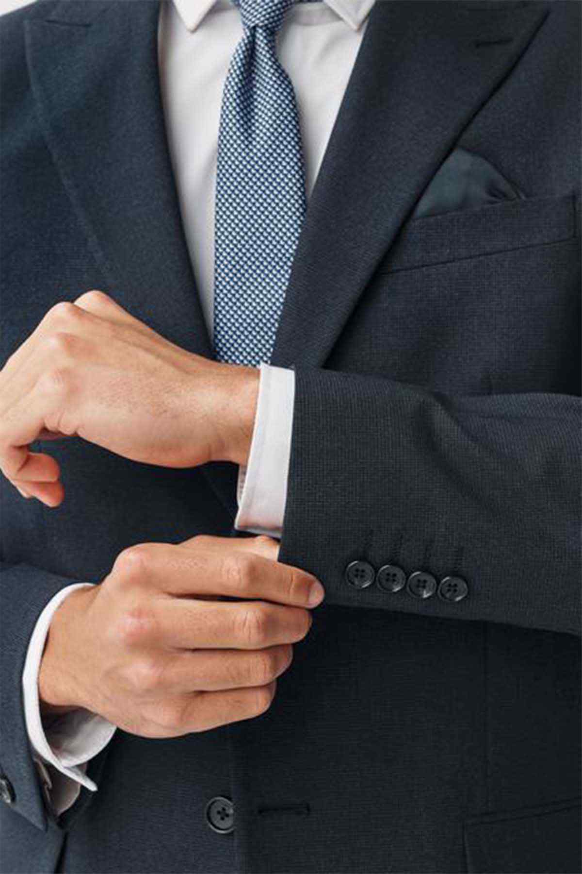 Navy suit jacket sleeve detail with buttoned cuff and shirt cuff peeking out