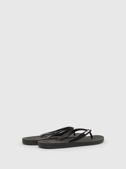 Pair of black flip-flops viewed from side, slim rubber thong straps