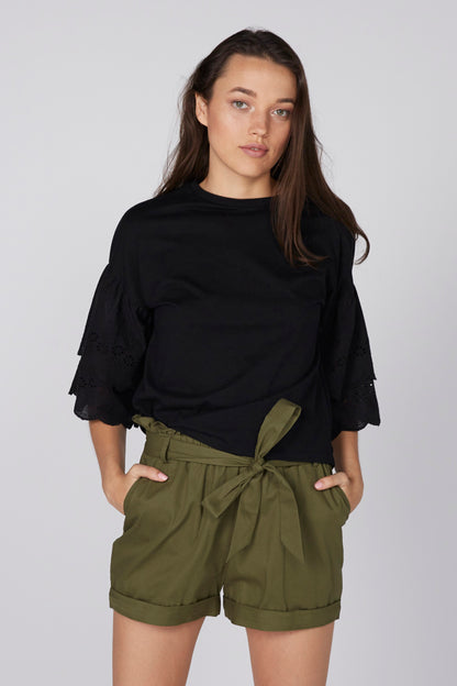 Black blouse with flared eyelet sleeves and olive belted shorts