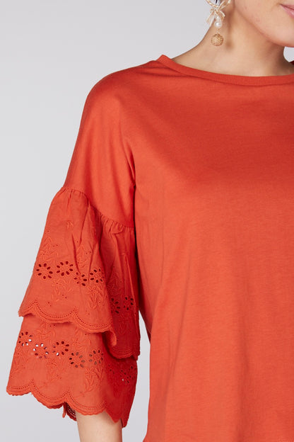 Orange blouse sleeve with eyelet lace cutouts and scalloped hem
