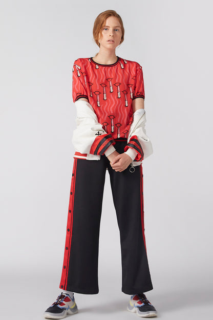 Red patterned sweatshirt with white sleeves, black wide-leg pants with red stripe down sides.
