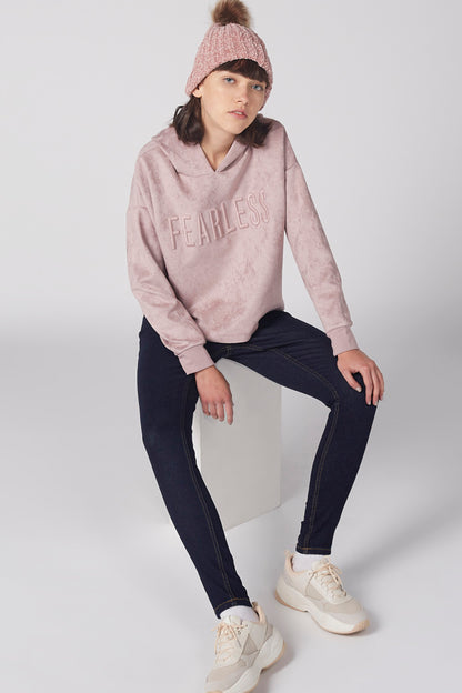 Pink hooded sweatshirt with 'FEARLES' print, hood up, worn with dark jeans