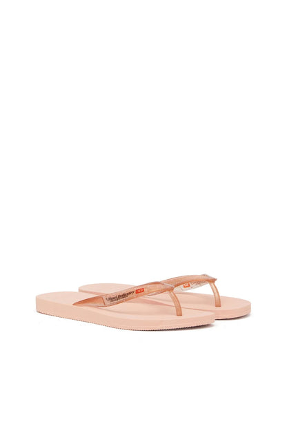 Diesel copper-toned flip-flops side view with logo patch on strap.