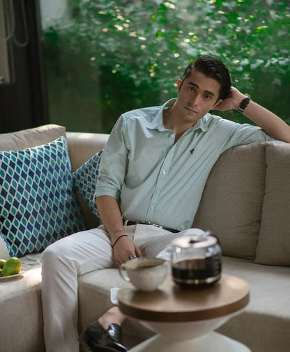 Men's striped button-up shirt with white pants and belt, reclining pose