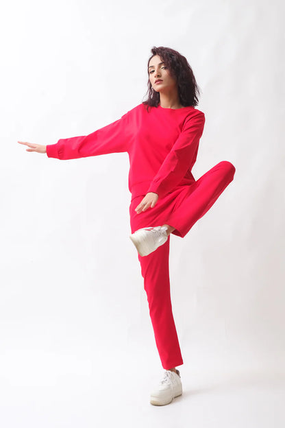 Red tracksuit set with crew-neck long-sleeve top and ankle jogger pants, one knee up