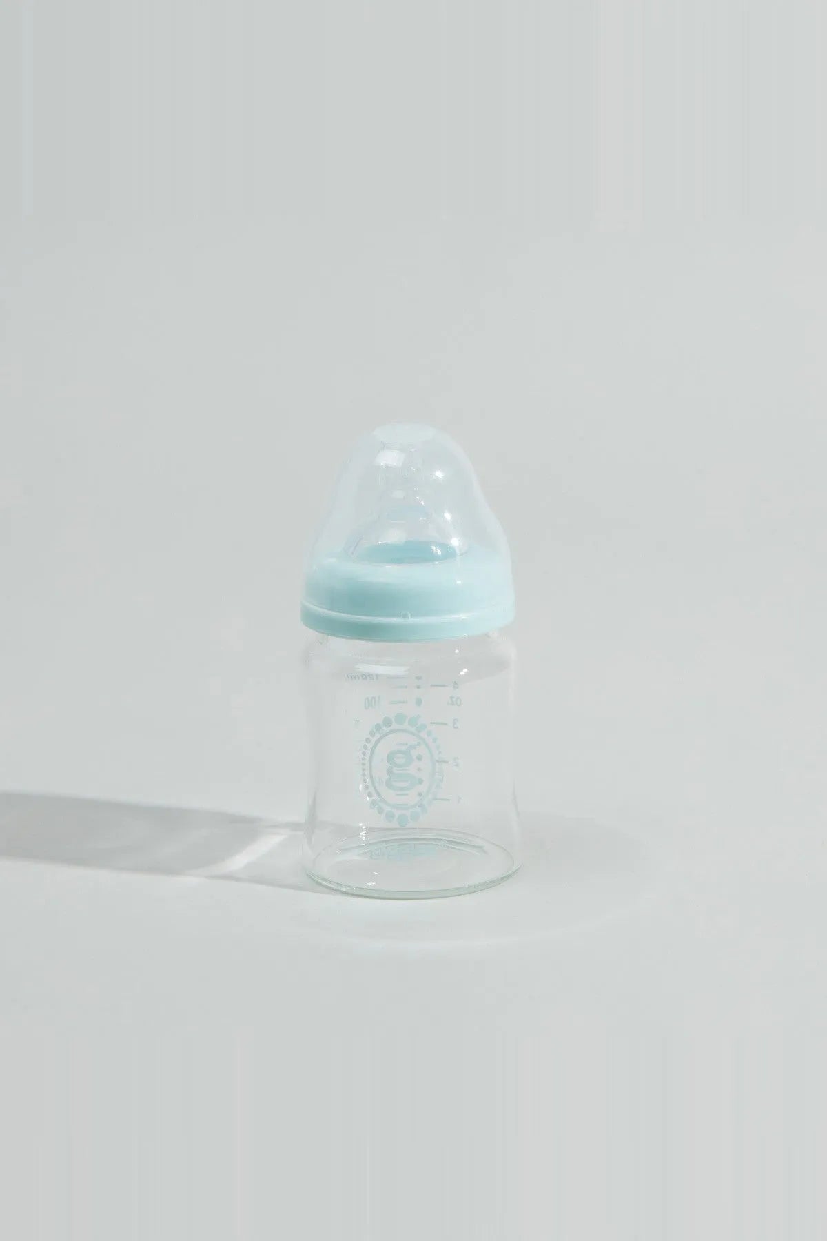 Baby bottle with blue cap, clear body, and nipple, side view