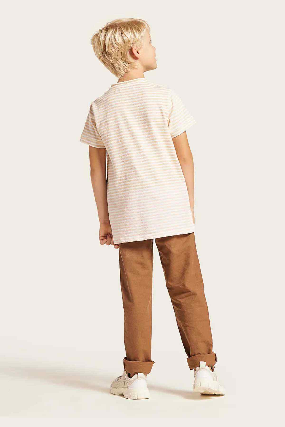 Kids striped short-sleeve top with brown pants and white sneakers, side view
