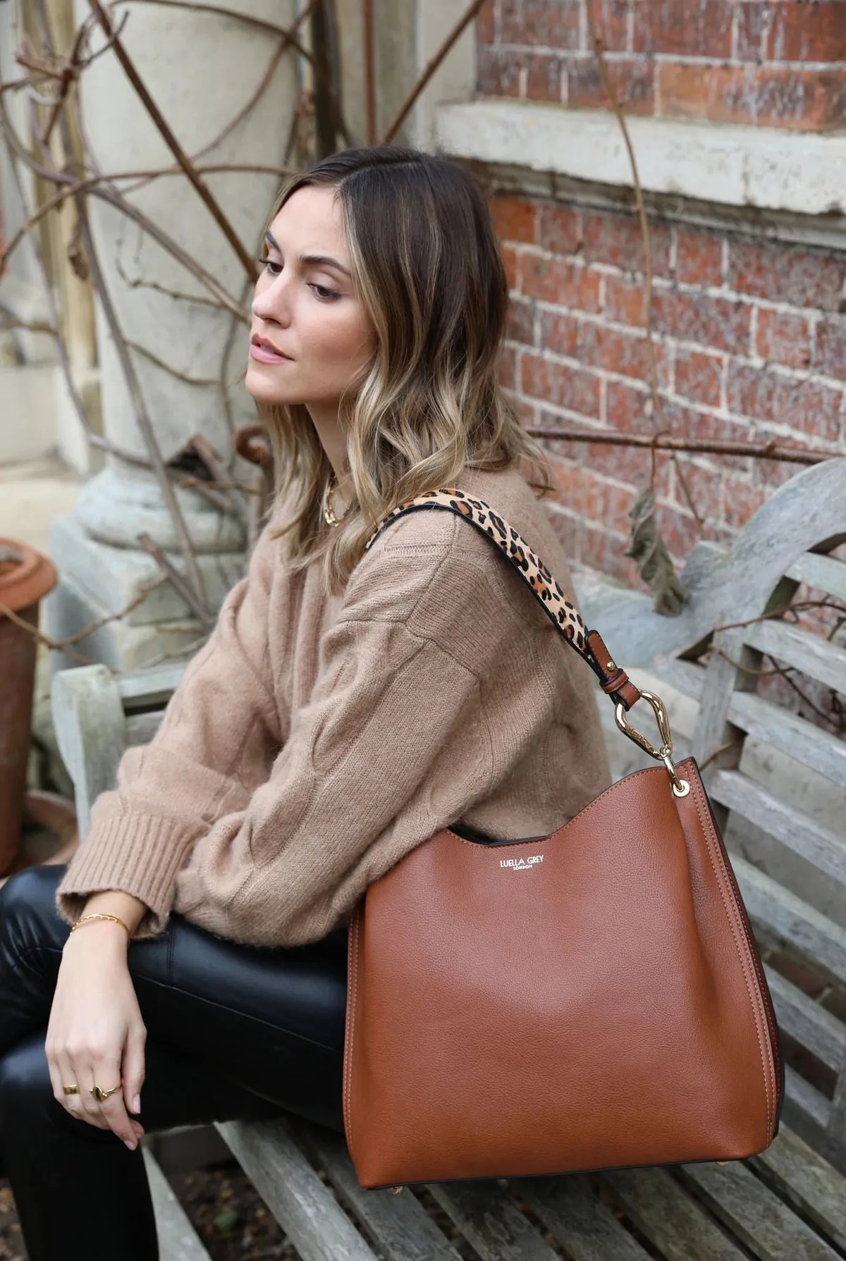 Brown leather hobo shoulder bag worn on shoulder with leopard print strap