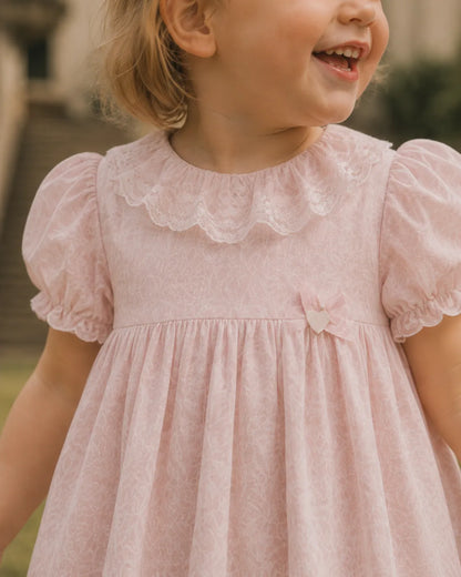 Light pink toddler dress with lace yoke, puff sleeves, and bow at waist