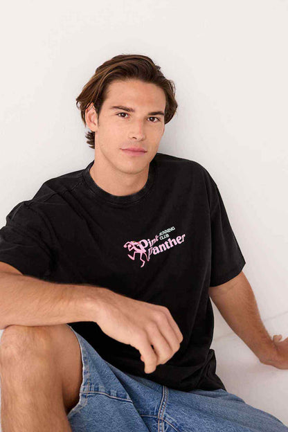 Black crew-neck T-shirt with Pink Panther running club logo, seated view