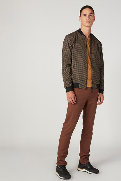 Beige houndstooth bomber jacket worn with matching brown trousers