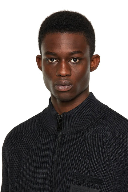 Close-up of black knit zip jacket with stand collar and chest patch