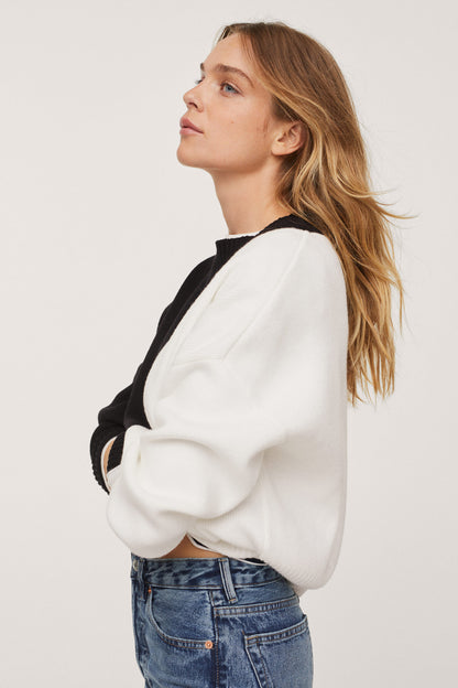 Two-tone crewneck knit sweater with black and white panels, long sleeves, ribbed cuffs.