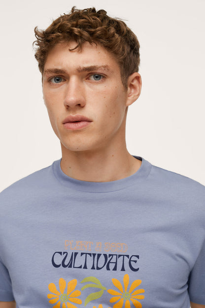 Men's blue crewneck T-shirt close-up of 'Cultivate' yellow flower graphic