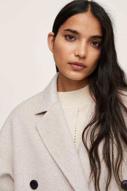 Light pastel gray overcoat collar detail with dark buttons and knit top