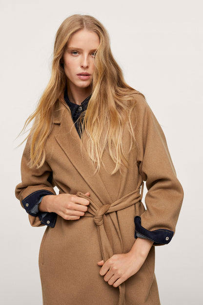 Tan belted long coat with dark cuffs, tie belt at waist and lapels