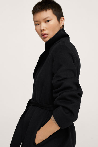 Black long coat with tie belt and wide lapel collar, side profile