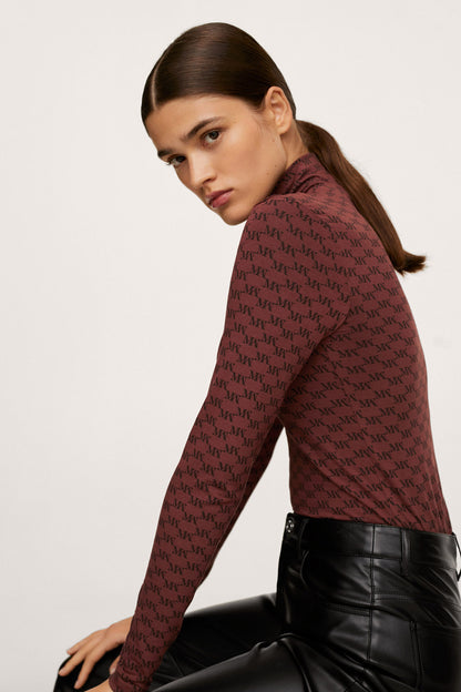 Burgundy patterned high-neck top with long sleeves, paired with black leather trousers