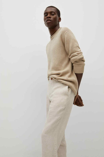 Ecru trousers on model, relaxed fit with straight legs and button closure.