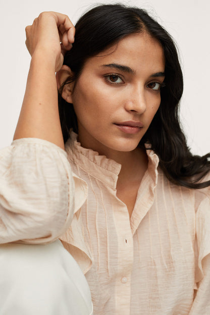 Ecru textured blouse with ruffled collar and button front
