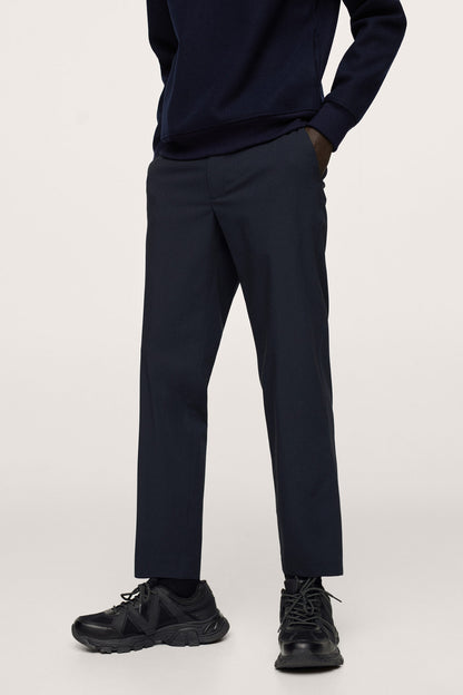 Dark navy straight-leg pants with cuffs and black sneakers, close-up lower half.
