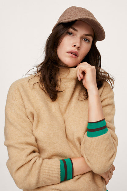 Beige sweater close-up with green striped cuffs and ribbed neckline